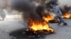 Afghanistan -- An Afghan boy runs next to fire during a protest in Jalalabad, 22Feb2012