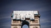 Workers unfurl massive rolls of blue fabric coated in &quot;pulverized aluminum&quot; as work gets under way on wrapping Paris&#39;s Arc de Triomphe on September 12.