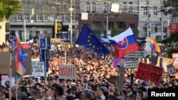 Mii de oameni au participat la demonstrația de protest de la Bratislava din 13 august. La asemenea mitinguri, oamenii nu uită simbolurile care-l „supără” cel mai tare pe premierul Fico: steagul UE și al persoanelor LGBT+.