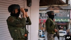 Soldați indieni păzesc o piață din Srinagar, în Kashmirul controlat de India.