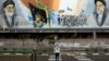 A man crosses an empty street under portraits of the late Iranian revolutionary founder Ayatollah Khomeini, right, and Supreme Leader Ayatollah Ali Khamenei, left, in Tehran, April 3, 2020