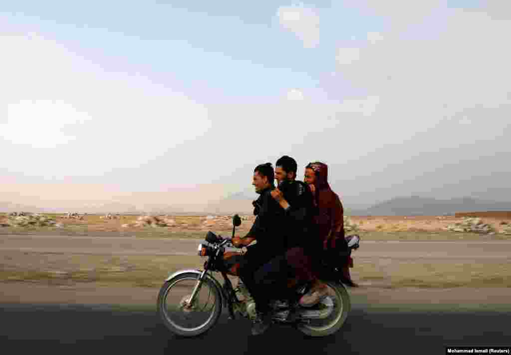 Afghan men ride a motorcycle on the outskirts of Kabul.