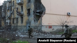 Військовослужбовці проходять повз житлові будинки, пошкоджені внаслідок російського удару по Костянтинівці, Донецька область, 7 грудня 2025 року