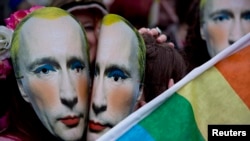 Протестующие в масках с изображением Владимира Путина у российского посольства в Лондоне во время митинга за права сексуальных меньшинств в России. 14 февраля 2014 года.