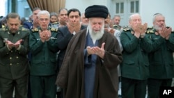 Iranian Supreme Leader Ayatollah Ali Khamenei (center) leads a prayer during his meeting with a group of senior military leaders in Tehran on April 21. 