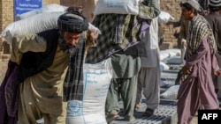 په افغانستان کې خلک د خوړو نړیوال پروګرام د مرستو وېش له ځایه د غنمو بوجۍ کورونو ته لېږدوي - انځور له ارشیفه. 