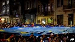 Mbështetësit e kandidatit presidencial Nicușor Dan mbajnë një flamur të Bashkimit Evropian pasi janë mbyllur kutitë e votimit për raundin e dytë të përsëritjes së zgjedhjeve presidenciale në Bukuresht, Rumani, të dielën, më 18 maj 2025.
