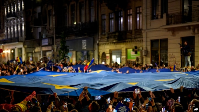 Mbështetësit e kandidatit presidencial Nicușor Dan mbajnë një flamur të Bashkimit Evropian pasi janë mbyllur kutitë e votimit për raundin e dytë të përsëritjes së zgjedhjeve presidenciale në Bukuresht, Rumani, të dielën, më 18 maj 2025.