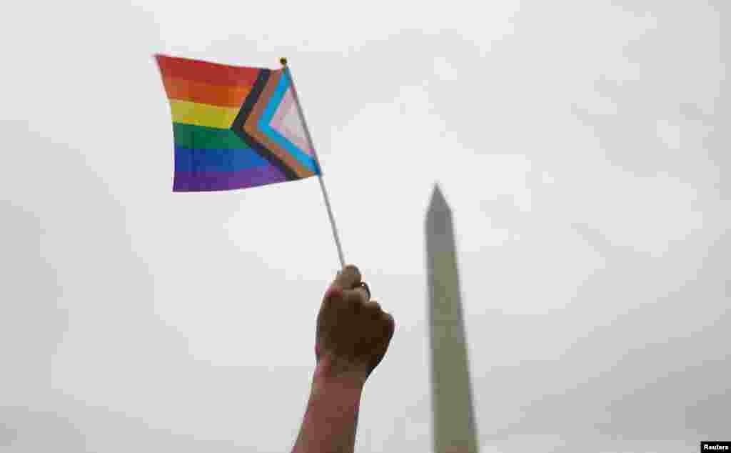 A washingtoni Pride egyik résztvevője emeli a magasba a szivárványos zászlót június 8-án