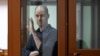 U.S. journalist Evan Gershkovich, accused of espionage, gestures from inside a glass defendants' cage prior to a hearing in Yekaterinburg's Sverdlovsk Regional Court on June 26.