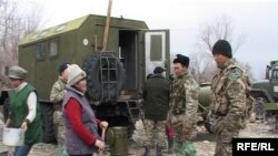 Kazakh soldiers talk to women who are preparing meals for flood victims on March 15, 2010.