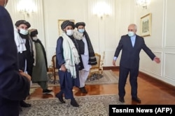 Zarif (right) walks with Mullah Baradar (center) in Tehran.