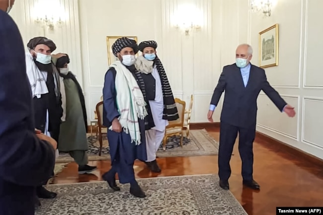 Zarif (right) walks with Mullah Baradar (center) in Tehran.