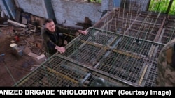 Ukraynalı hərbçilər dron pərlərini ilişdirmək üçün metal qəfəsə plastik məftillər quraşdırırlar.