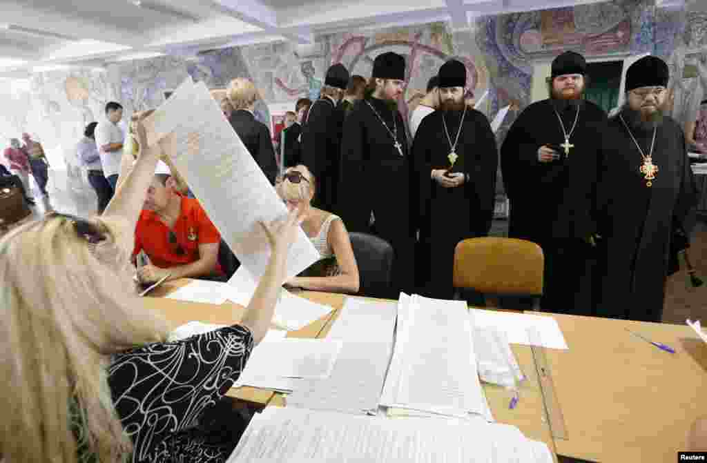 Priests queue to collect their ballot papers before voting at a polling station in the capital, Kyiv.