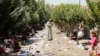 Iraq -- Displaced people from the minority Yazidi sect, fleeing the violence in the Iraqi town of Sinjar, rest as a man stands amongst garbage at the Iraqi-Syrian border crossing in Fishkhabour, Dohuk province, August 13, 2014