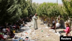 Iraq -- Displaced people from the minority Yazidi sect, fleeing the violence in the Iraqi town of Sinjar, rest as a man stands amongst garbage at the Iraqi-Syrian border crossing in Fishkhabour, Dohuk province, August 13, 2014