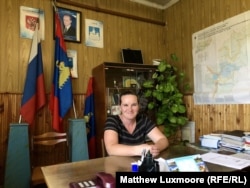 Marina Udgodskaya in her new office, flanked by a portrait of Russian President Vladimir Putin and a map of her political domain.