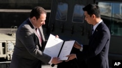 Japanese Deputy Defense Minister Toshiro Ino (right) hands a document about the donation to Serhiy Korsunsky, Ukraine's ambassador to Japan, at a ceremony in Tokyo on May 24. 