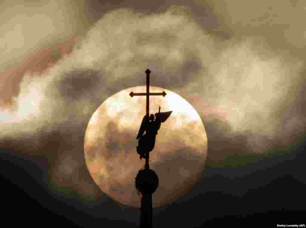 St. Petersburg&#39;s landmark weather vane, fixed atop a spire of the Saints Peter and Paul Cathedral, is silhouetted against the sun.