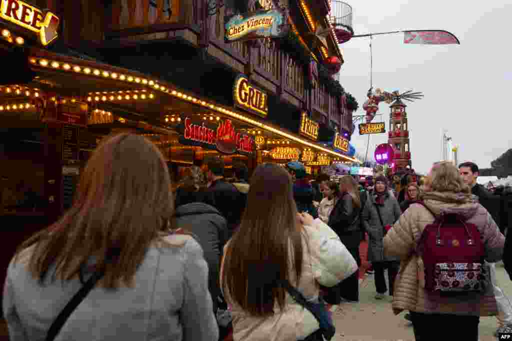 Vizitatorii stau la coadă pentru a cumpăra mâncare la târgul de Crăciun și parcul de distracții din grădinile Jardin des Tuileries, în centrul Parisului, pe 13 decembrie 2025.