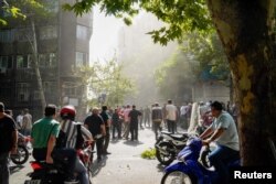 Ljudi se okupljaju na ulici usred dima nakon izraelskih napada na Iran, u Teheranu, Iran, 15. juna 2025.