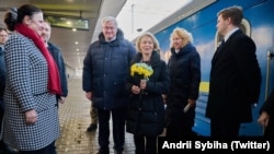Ursula von der Leyen, cu un buchet de flori în mâini, întâmpinată pe peronul gării din Kiev de delegația ucraineană, 24 februarie 2026