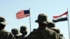 US troops stand to attention in front of American and Iraqi (R) flag. May 15, 2020