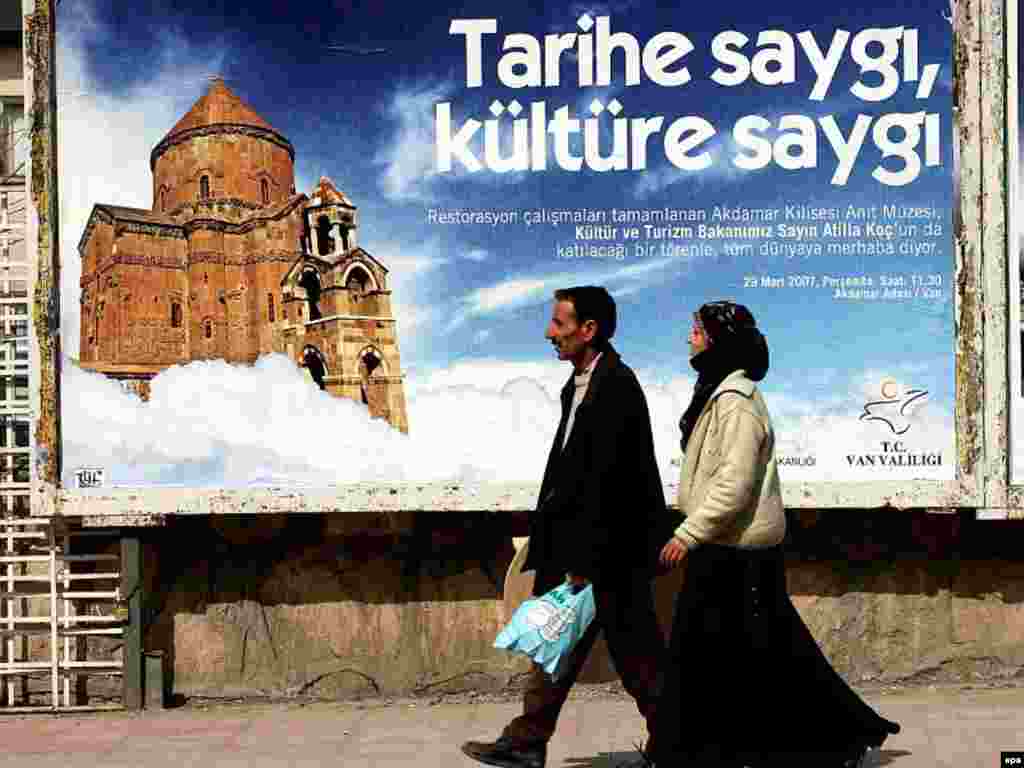 A Turkish couple walks past a billboard with an image of Armenian 1 000-year-old Akhtamar Church one of the finest surviving monuments of ancient Armenian culture with text 'Respect to history respect to culture' in Van eastern Turkey Wednesday 28 March 2007. Turkey has completed a $1.5 million restoration of the sandstone building and has invited Armenian officials to a ceremony there on 29 March