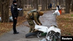 Ukrainian police officers in a park in Kyiv inspect part of a Russian cruise missile, which was intercepted during a a strike on the country's capital early on March 24.