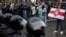 A man carrying the former white-red-white flag of Belarus stands in front of riot police during a rally to protest against the presidential election results in Minsk on October 11, 2020.