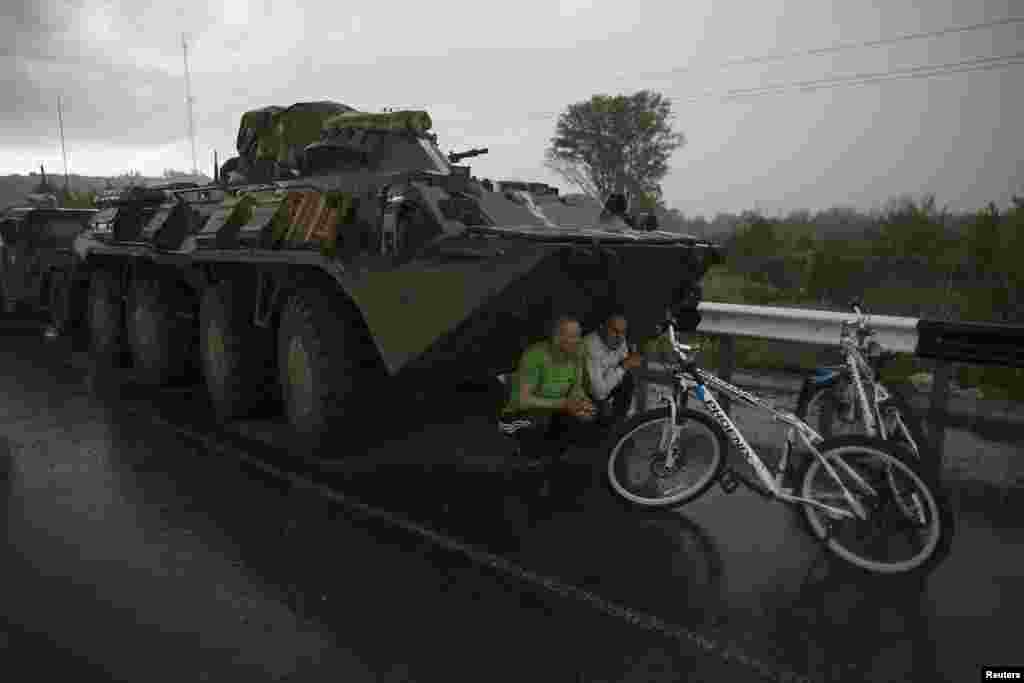 Ukrainian civilians find cover from the rain under a Ukrainian Army armored personnel carrier at a checkpoint near the town of Slovyansk on May 2. (Reuters/Baz Ratner )