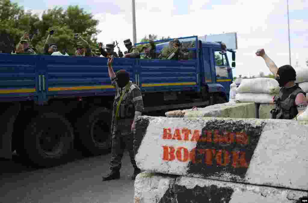 Pro-Russian separatists of the self-proclaimed &#39;Vostok Battalion&#39; cheer their comrades on a truck at a checkpoint on the outskirts of the city of Donetsk. No polling stations have opened in the city of Donetsk.