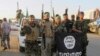 Shi'ite fighters pose with a black flag belonging to the Islamic State, which they pulled down after capturing the town of Jurf al-Sakhar from the Islamist militants on October 26.