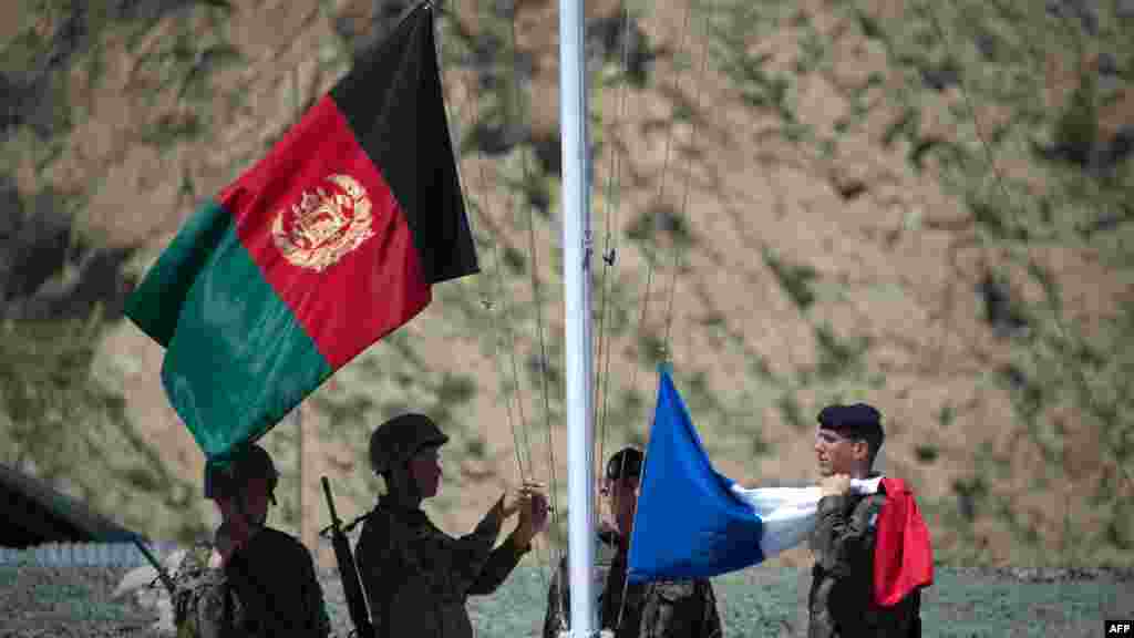 Afghan National Army soldiers raise their national flag next to the French flag during a transition ceremony at a Surobi military facility on April 12. (AFP/Johannes Eisele)