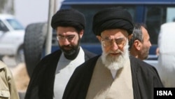 علی خامنه‌ای، رهبر کشته‌شدهٔ جمهوری اسلامی، و پشت سر او، مجتبی که به جانشینی‌اش انتخاب شده است